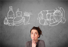 pretty woman standing in front of a chalk board, deciding between fast food and healthy food images