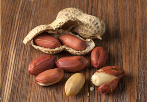 whole and shelled peanuts on a wooden table