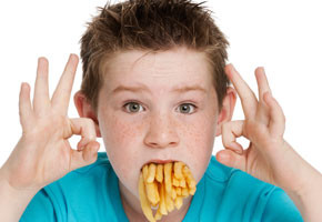 Young boy with a mouth crammed full of fries