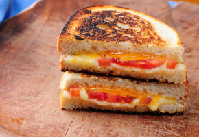 classic grilled cheese and tomato sandwiches on a wooden platter