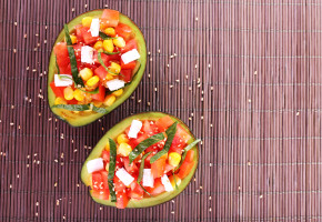 Tasty salad in avocado on bamboo napkin close-up